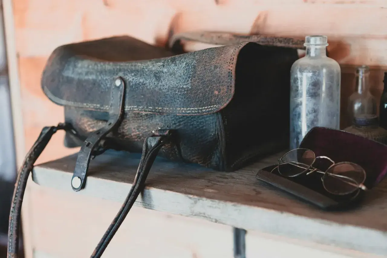 Sacoche en cuir moisi, lunettes anciennes et flacons poussiéreux sur une étagère. Le bicarbonate de soude pourrait aider à rafraîchir ce cuir.