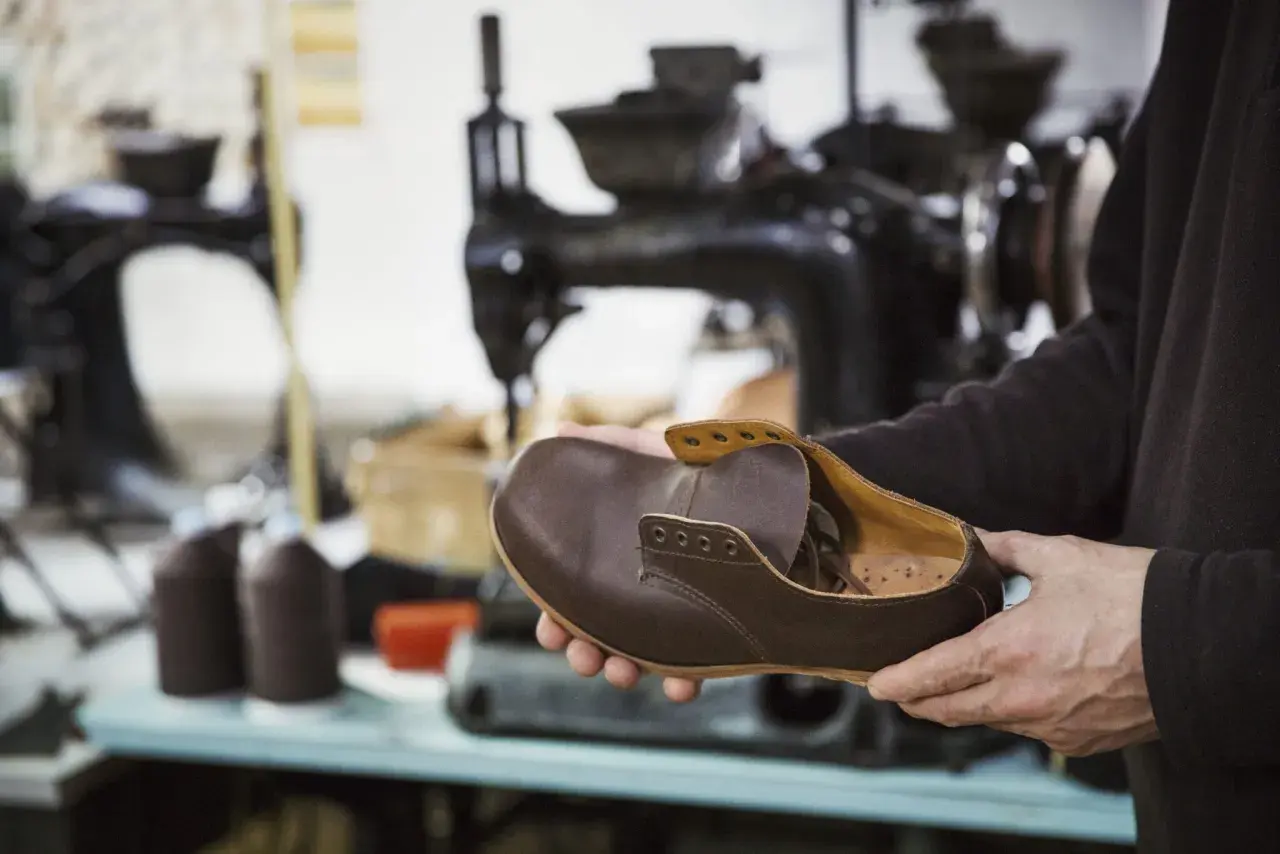 Un artisan examine une chaussure de ville en cuir marron, signe qu'il est temps de penser à quand changer ses chaussures de ville.