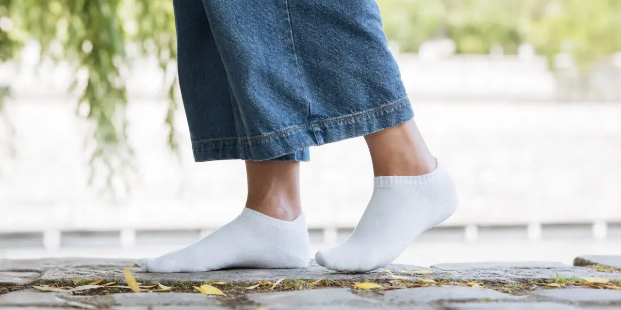 Pieds féminins en chaussettes blanches discrètes, idéales avec des baskets blanches pour un look casual.
