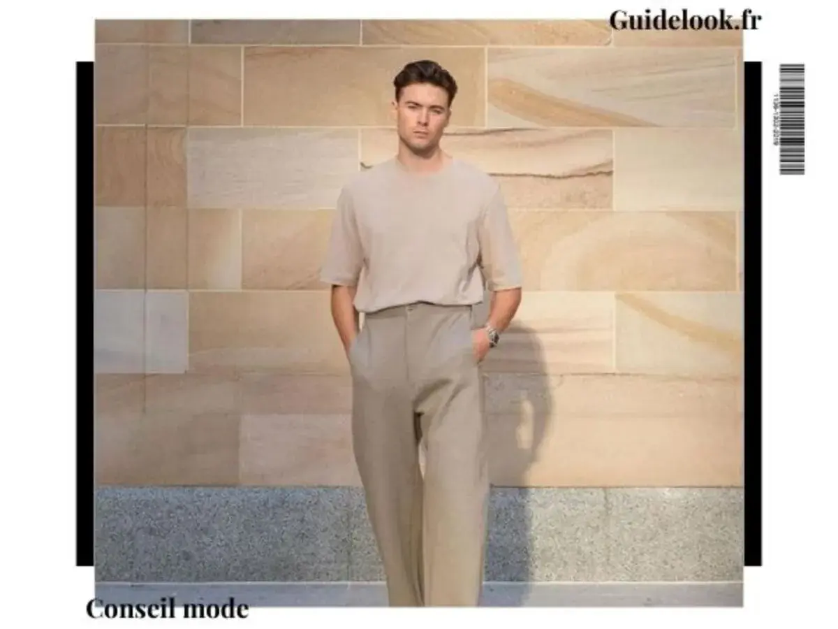 Un homme grand et mince porte un t-shirt beige et un pantalon ample. Un look parfait pour savoir comment s'habiller quand on est grande et mince.