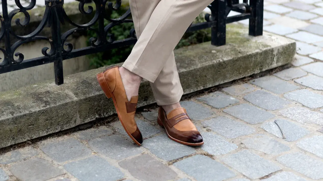 Un homme porte des mocassins bicolores en cuir, un style parfait pour une promenade en ville. Pas de marron dans la ville, juste du style !