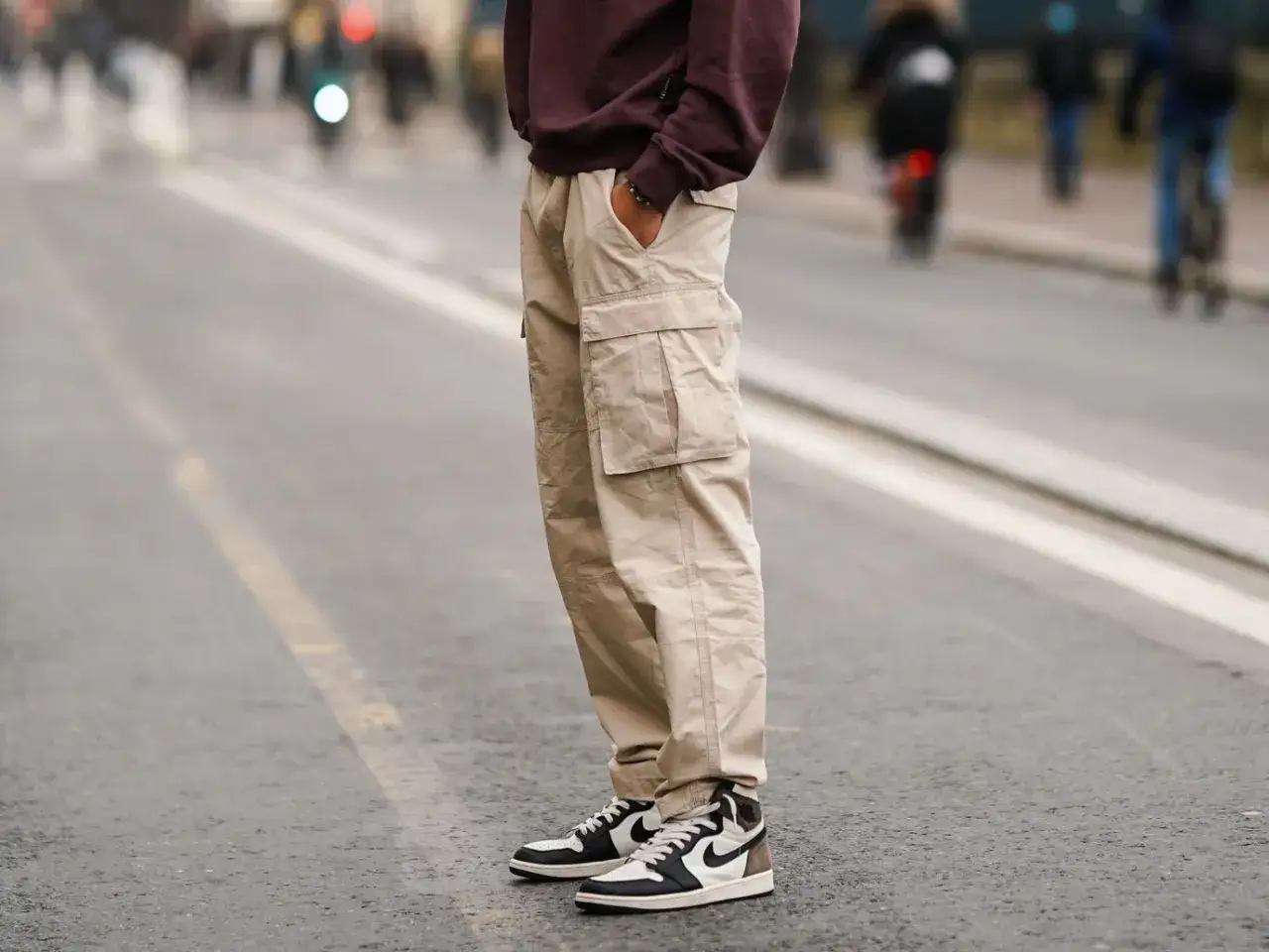 Un homme porte un pantalon cargo beige et une chaussure de sport tendance, prêt pour une journée en ville.