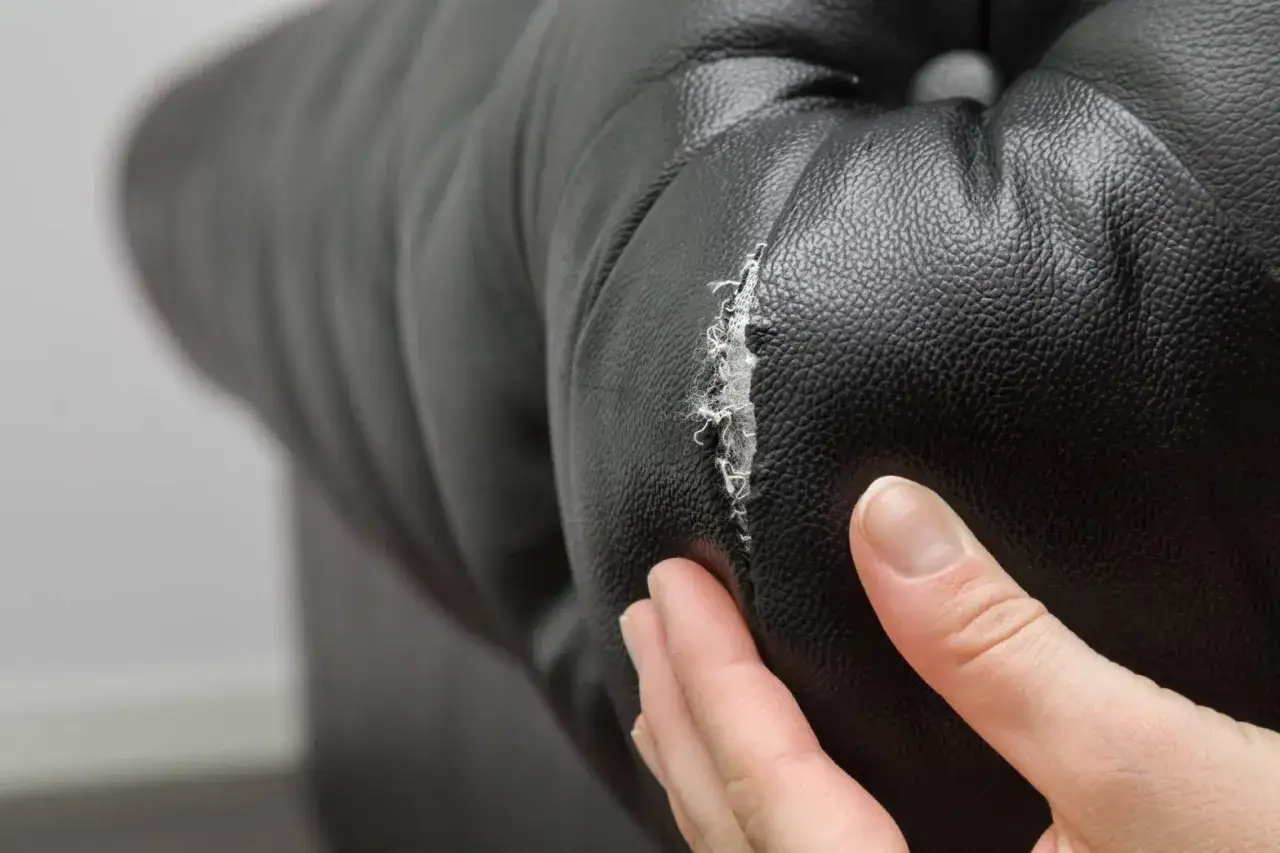 Gros plan sur un accroc sur un fauteuil en cuir noir, révélant les fibres internes.
