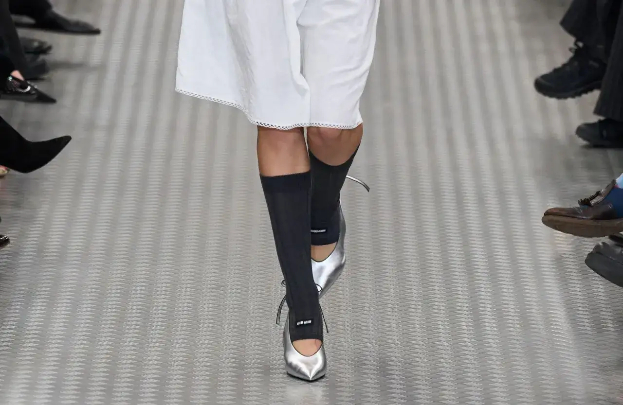 Une tenue avec des chaussures argentées, des chaussettes hautes grises et une robe blanche.