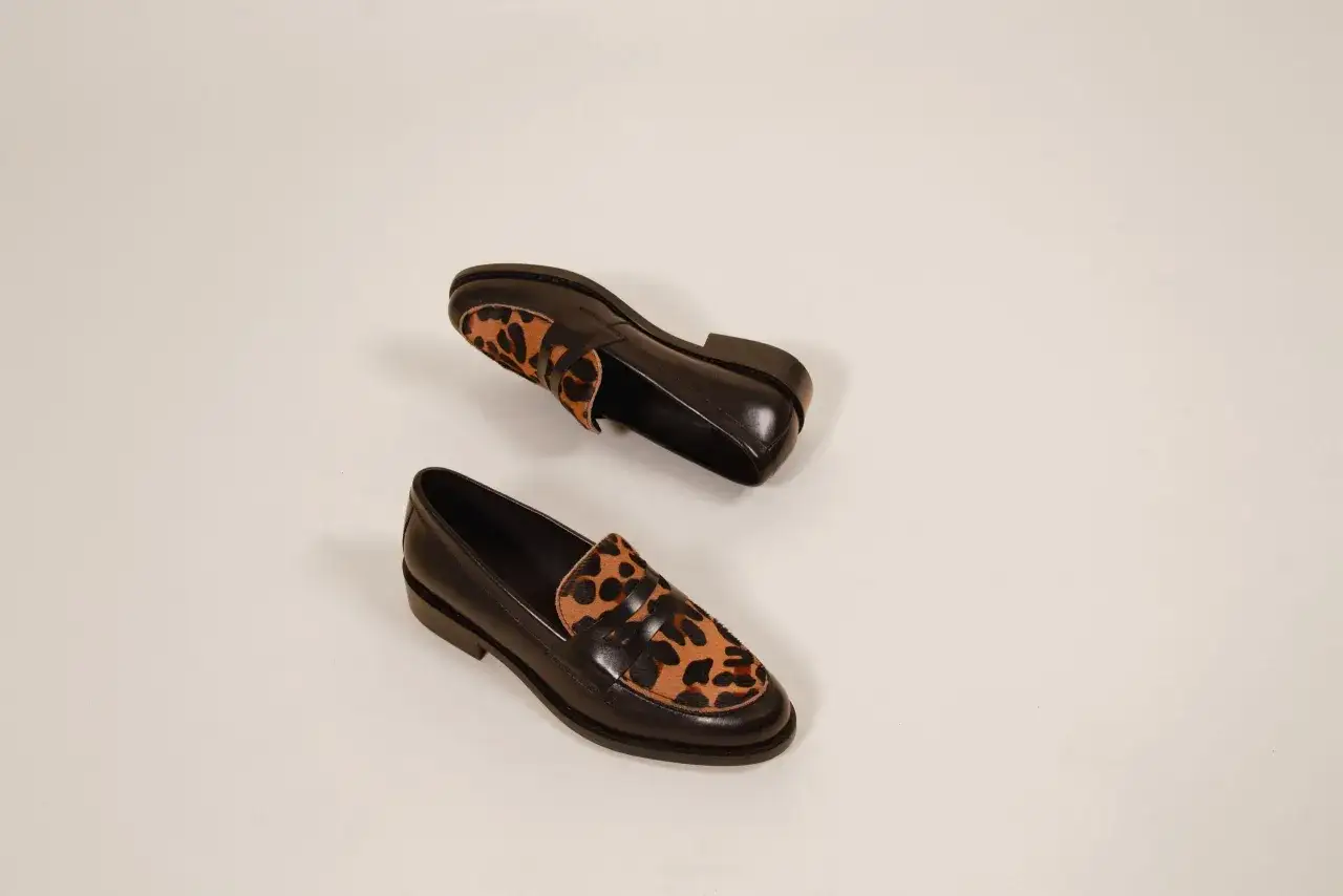 Une paire de mocassins noirs avec un empi&egrave;cement l&eacute;opard. Une chaussure &agrave; avoir pour un look audacieux.