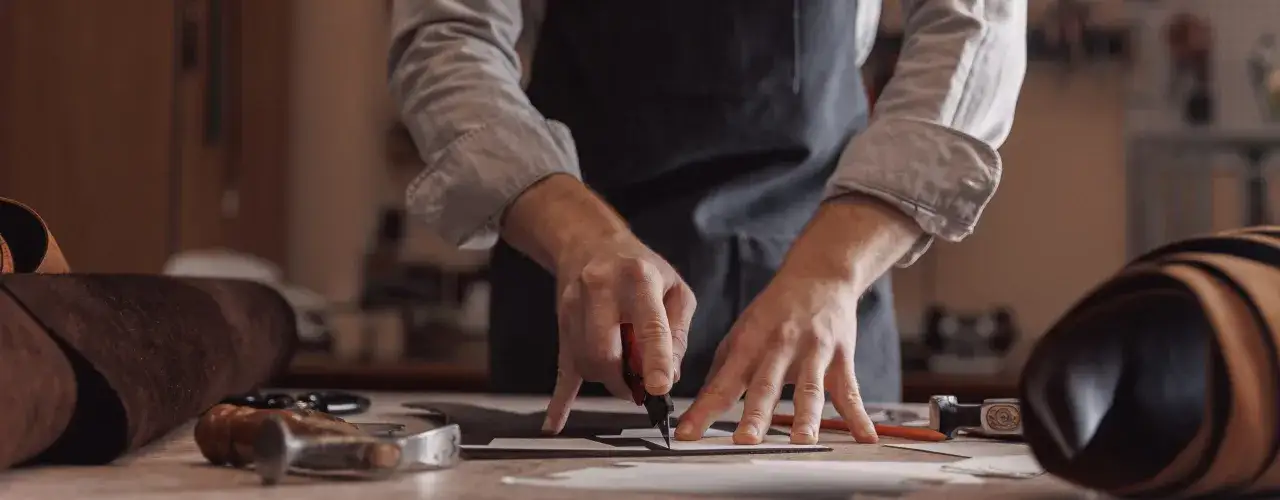 Artisan travaillant le cuir, un aperçu de la liste des tanneries en France. Outils et peaux à portée de main.