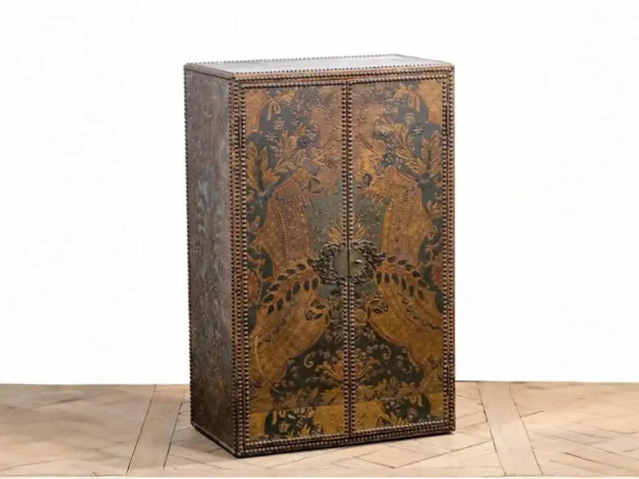 Armoire ancienne ornée de motifs complexes sur du cuir de Cordoue, avec des volutes et des figures d'oiseaux stylisés.