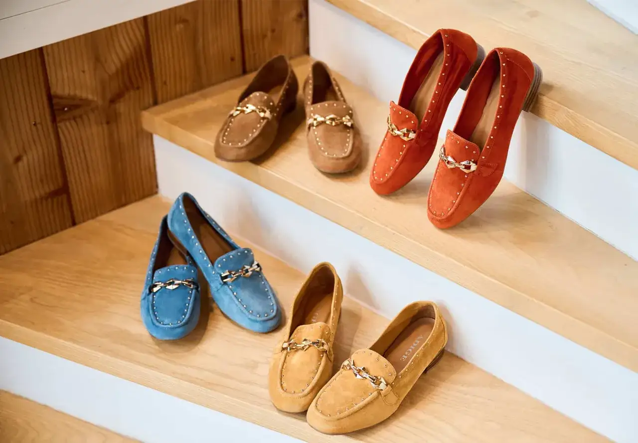 Des mocassins en daim bleu, marron, orange et jaune, ornés de clous et d'une chaîne dorée. Une chaussure qui va avec tout, parfaite pour toutes vos tenues.