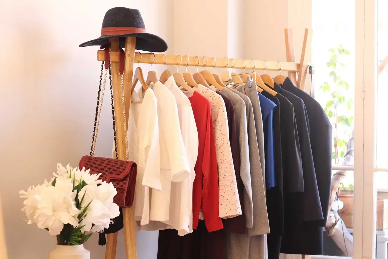 Un portant &agrave; v&ecirc;tements bien organis&eacute;, avec un chapeau et des sacs, illustre comment &eacute;viter la surconsommation en privil&eacute;giant la qualit&eacute; et la polyvalence.