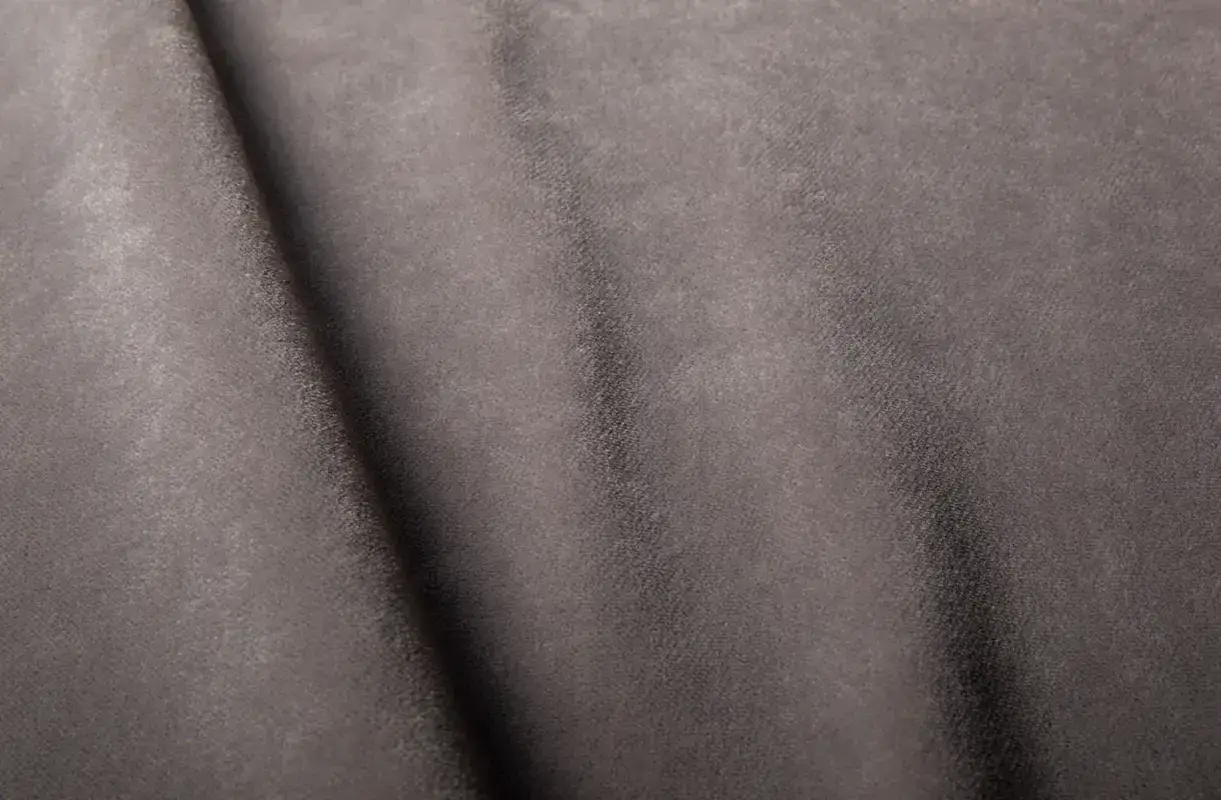 Plis doux et texturé de cuir retourné gris. La lumière joue sur les reflets subtils de la matière.