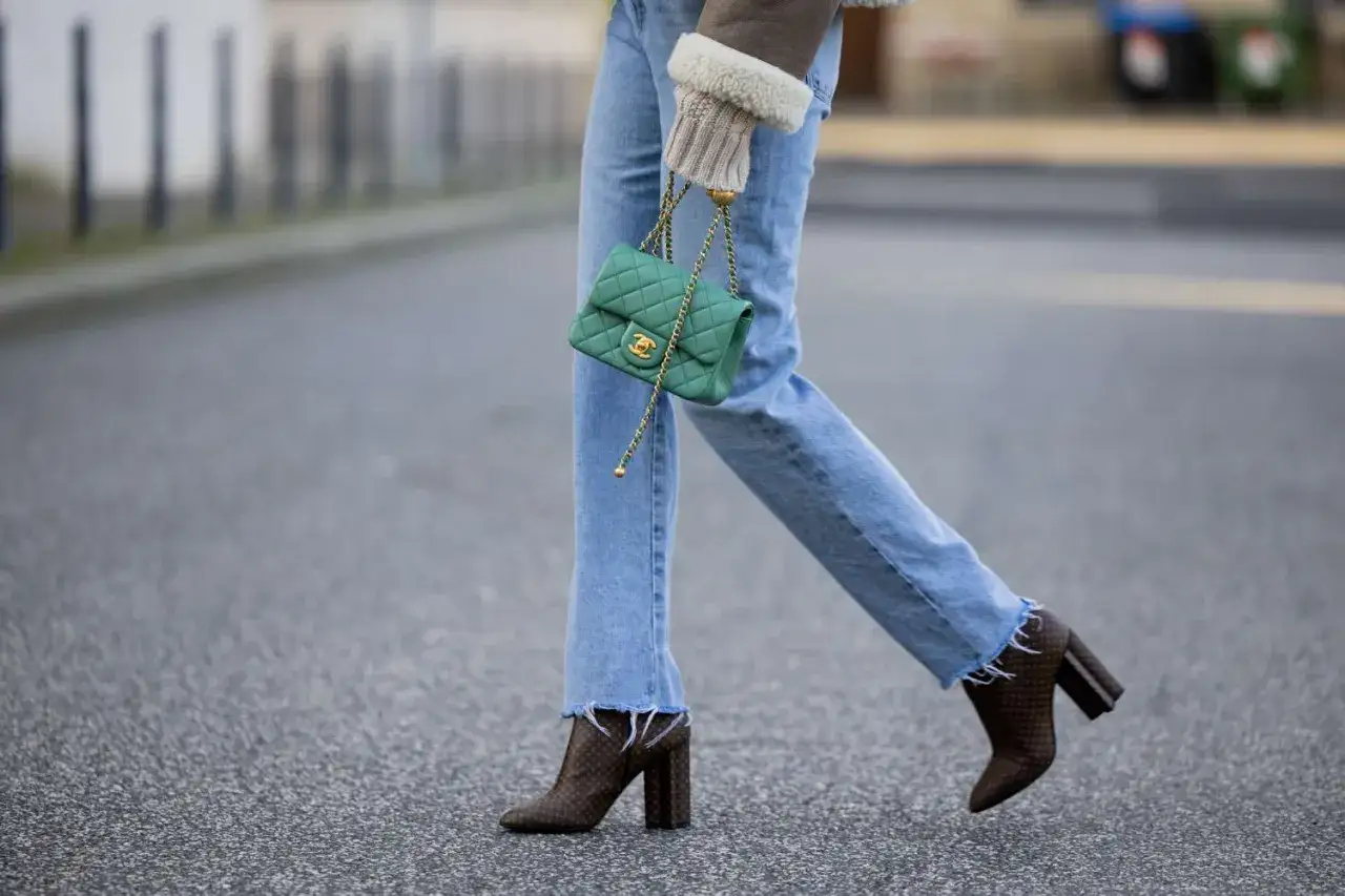 Comment porter des bottines avec un jean : un look chic avec un sac vert émeraude et des bottines imprimées.
