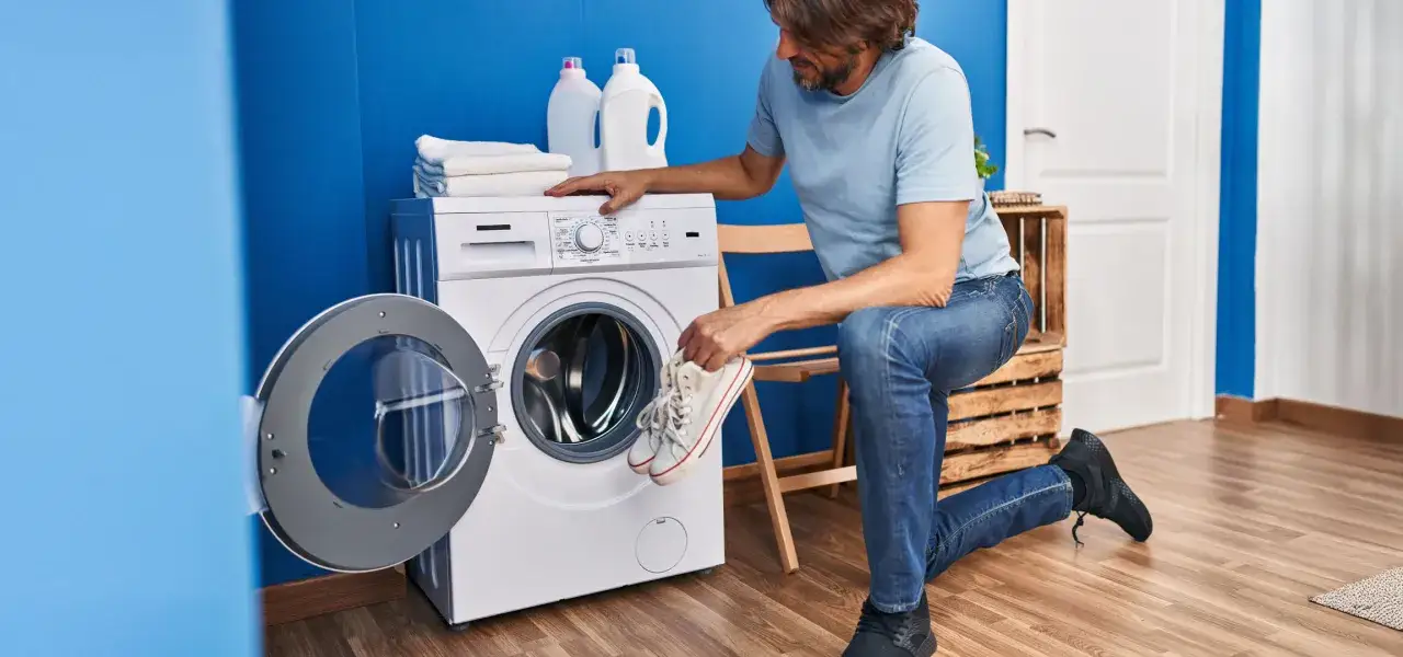 Un homme prépare ses baskets pour un lavage en machine. Il se demande à combien laver des chaussures pour qu'elles ressortent comme neuves.